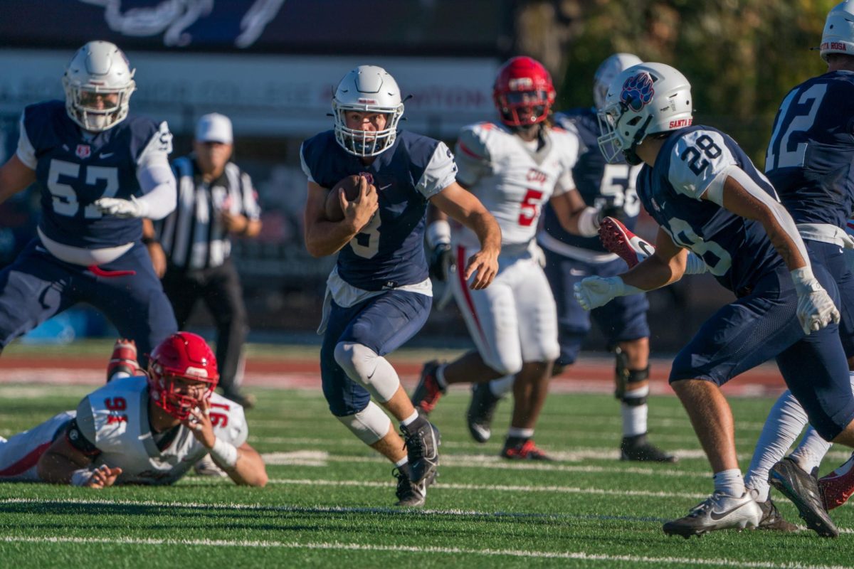 Quarterback Chase Vehmeyer bolts down the field in possession of the ball as CCSF's Eric Waugh is brought down to the ground courtesy of Bear Cub offensive lineman Jackson Davenport on Bailey Field on Saturday, Sept. 7, 2024.