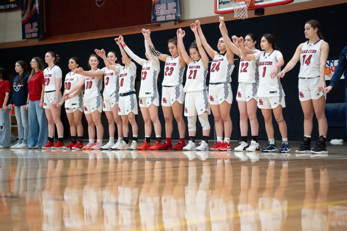 The Bear Cubs raises their arms at the end of the national anthem before their match against American River College at Haehl Pavilion on Friday, Feb. 21, 2025.