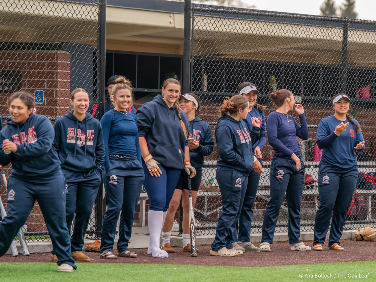 The current softball roster looks on with glee as head coach Madison Green is up to bat at the Alumni Home Run Derby on Saturday, March 15, 2025 in Santa Rosa.