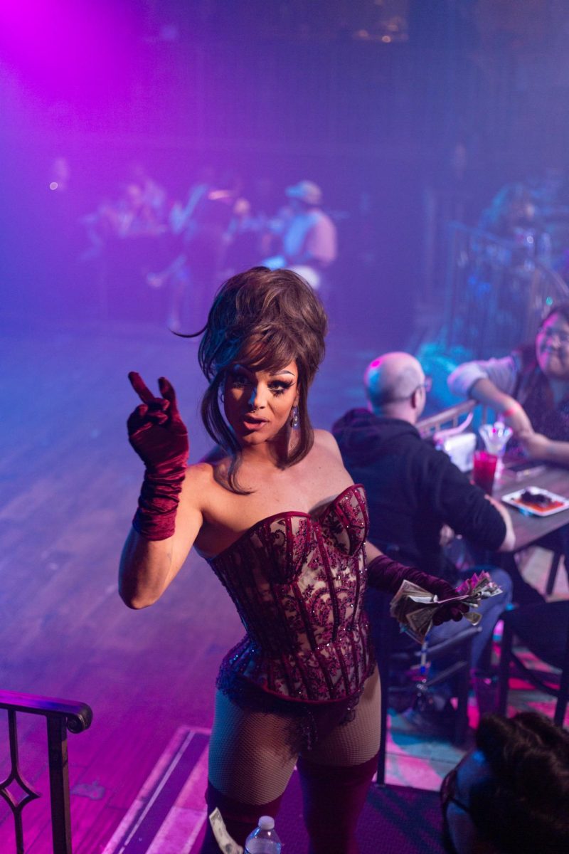 April Carrion gives a playful piece sign to a patron after receiving a tip during a performance at Hamburger Mary's in Long Beach, California on March 7, 2025.