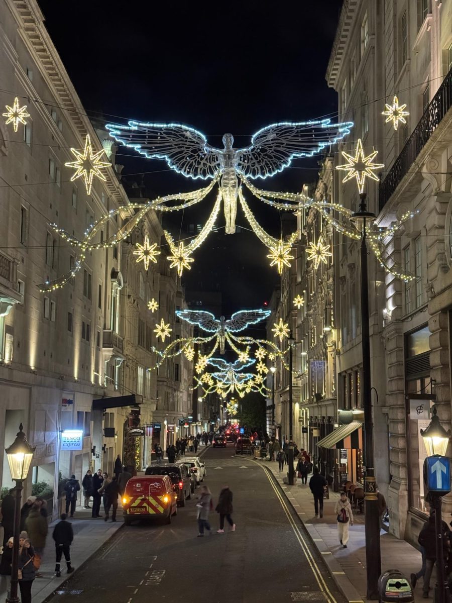 The iconic angels of Soho glimmer at night while shoppers shuffle through the crowded streets. 
