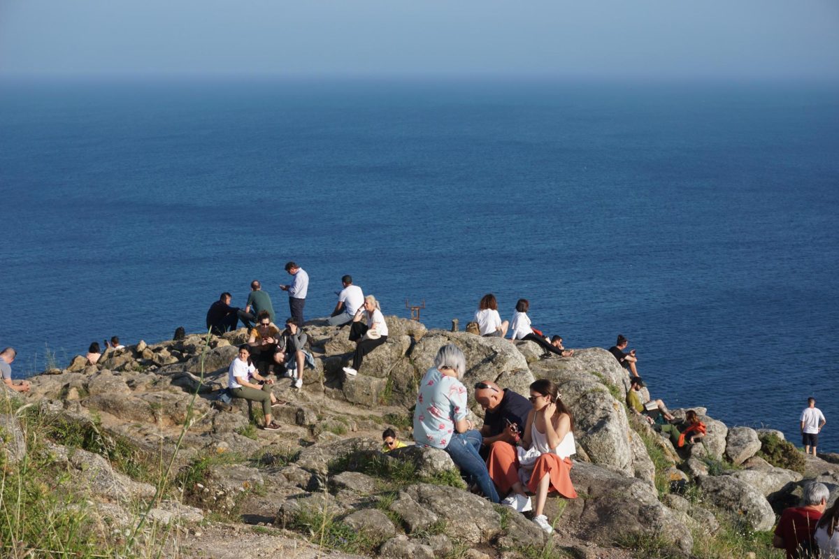 Tourists and hikers wait to watch the sun sink into the Atlantic ocean together on June 25, 2023.