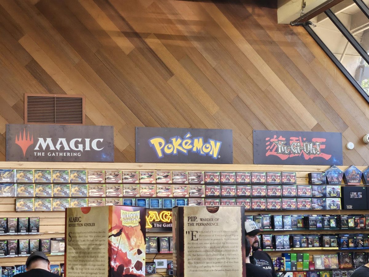 Signs above the shelves at OP Comics and Games show the three most popular card games.