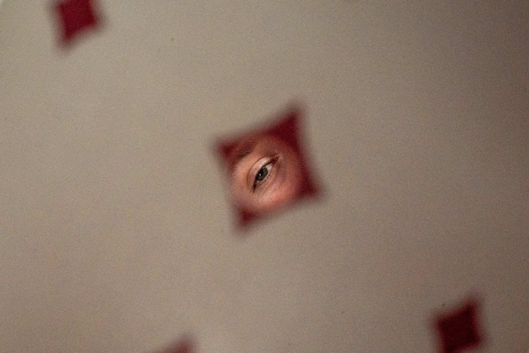 The weary eye of a gambler shines through a five of diamonds in the never-ending quest to get-rich-quick - or at least cover college tuition. 