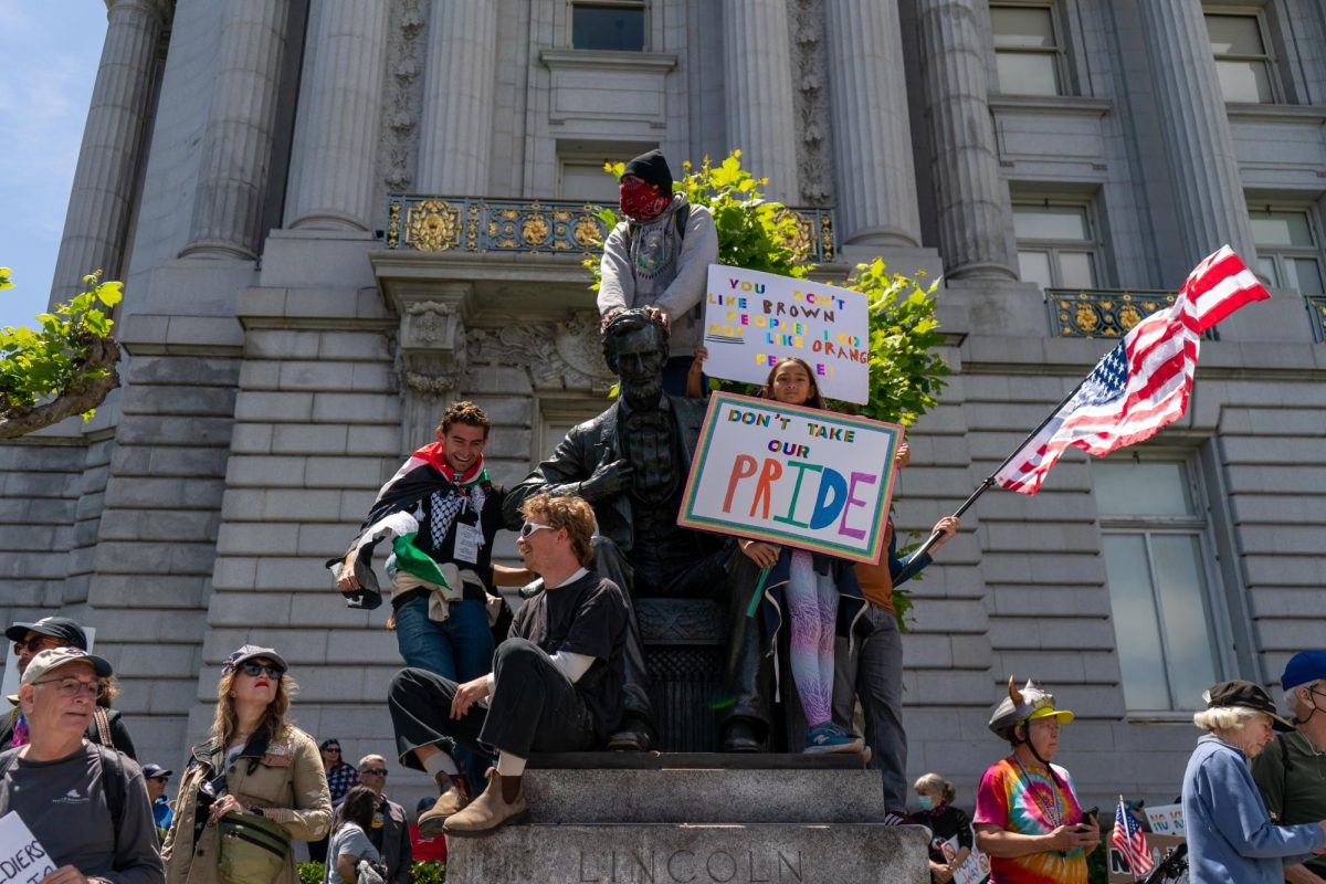 Protesters young and old climb on top of a statue of Abraham Lincoln at Civic Center Plaza during "No Kings Day" on Saturday, June 14, 2025 in San Francisco.