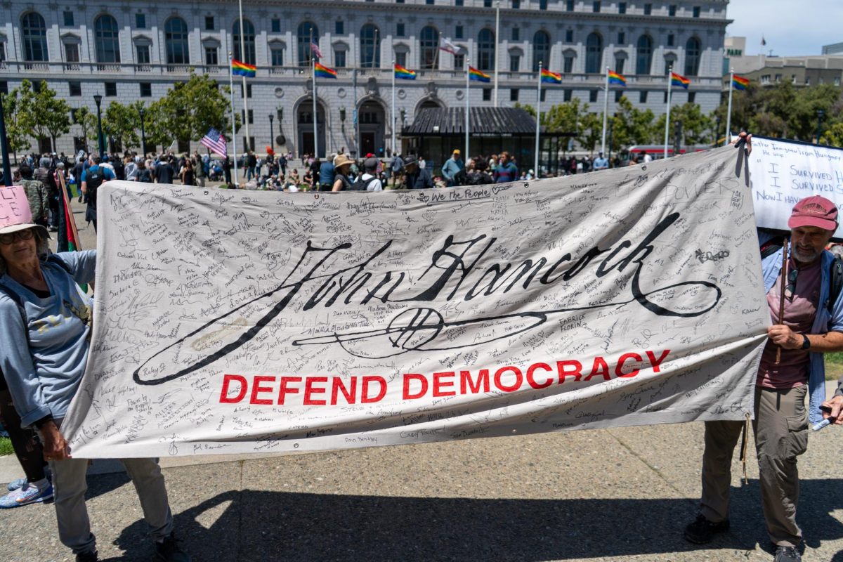 Protestors ask others to sign their John Hancock banner at Civic Center Plaza for "No Kings Day" on Saturday, June 14, 2025 in San Francisco.
