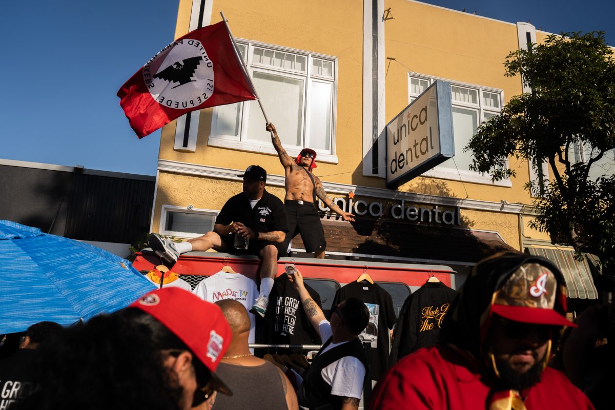Attendee Oso waves a United Farm Workers flag during the King of the Streets lowrider parade on Mission Street in San Francisco on Saturday, Sept. 20, 2025.