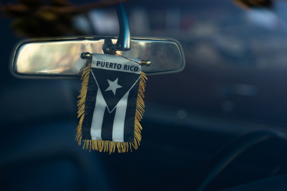 A Puerto Rican flag is hung up on a lowrider's rear-view mirror, during the King of the Streets lowrider parade on Mission Street in San Francisco on Saturday, Sept. 20, 2025. While lowrider culture is associated with people of Mexican-American descent, car enthusiast representing countries and territories throughout Latin America flavored the King of the Streets car show.