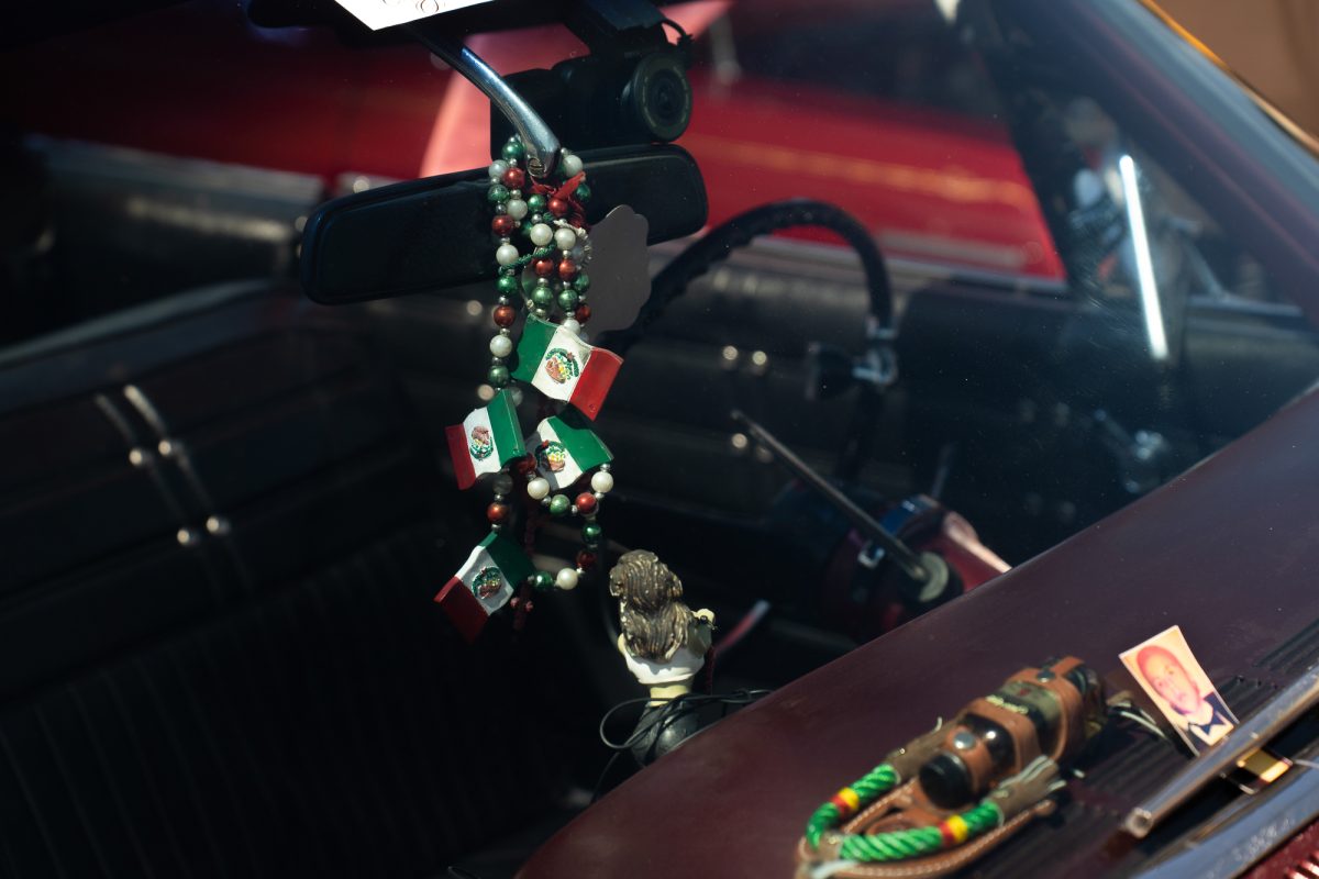 A rosary decorated with Mexican flags dangles over the dash of a lowrider, during the King of the Streets lowrider parade on 24th and Mission streets in San Francisco on Saturday, Sept. 20, 2025.