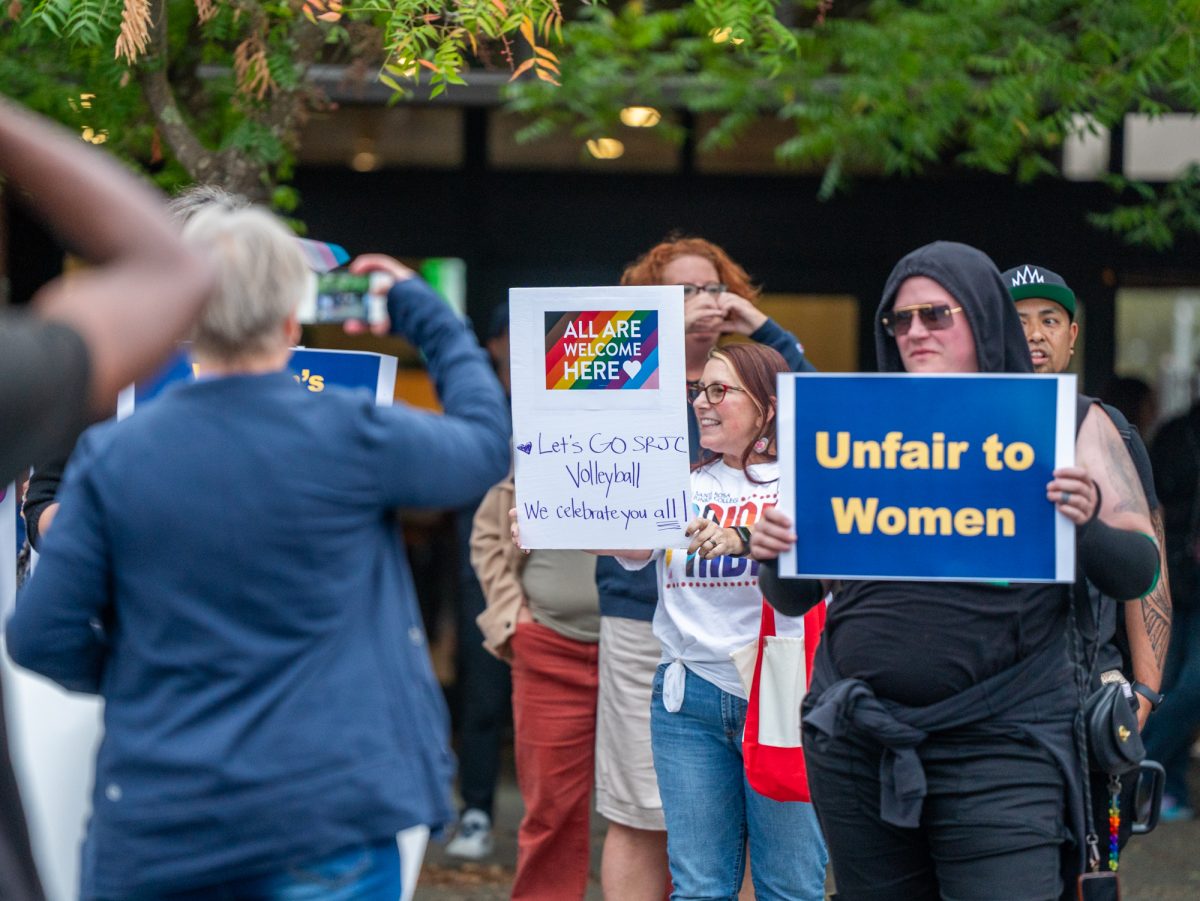 A mix of signs in support and opposition of a trans athlete on the SRJC women's volleyball team line the front of Haehl Pavilion on Wednesday, Oct. 8.