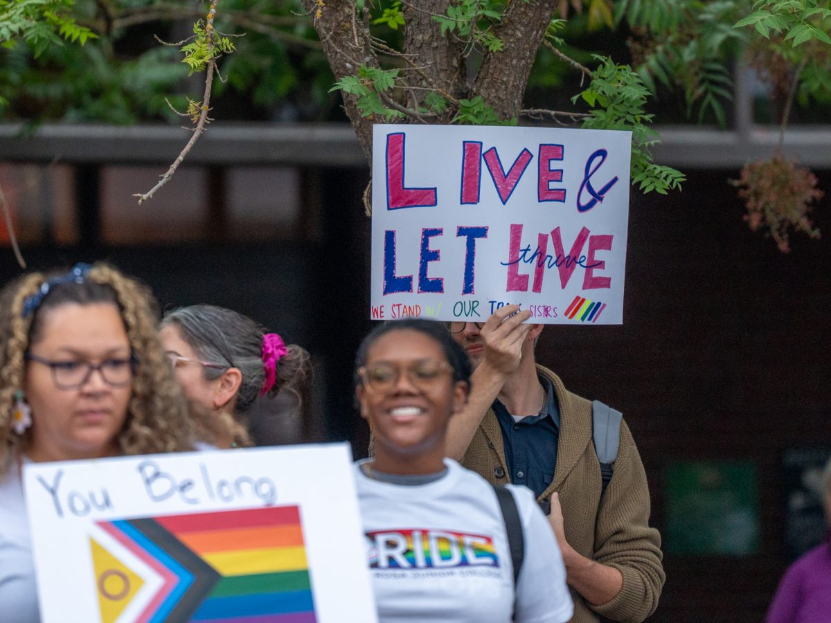 A sign with the message "Live and Let Live/Thrive, We Stand With Our Trans Sisters" is held during a demonstration ahead of Wednesday night's matches against American River on Wednesday, Oct. 8.