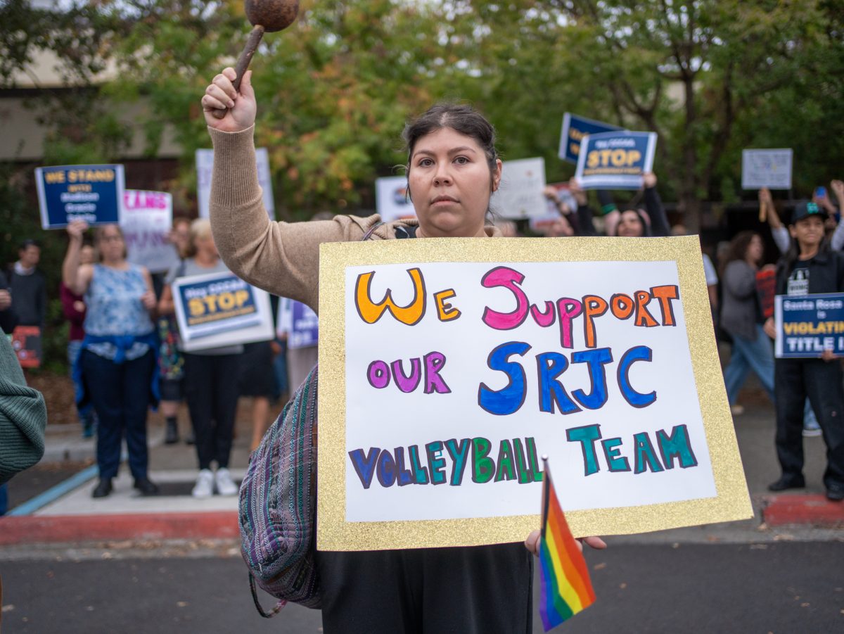 A supporter of a trans athlete's rights to participate on the SRJC women's volleyball team steps in front of the opposing demonstrators holding a sign that says "We support our SRJC Volleyball Team" ahead of Wednesday night's matches against American River on Wednesday, Oct. 8.