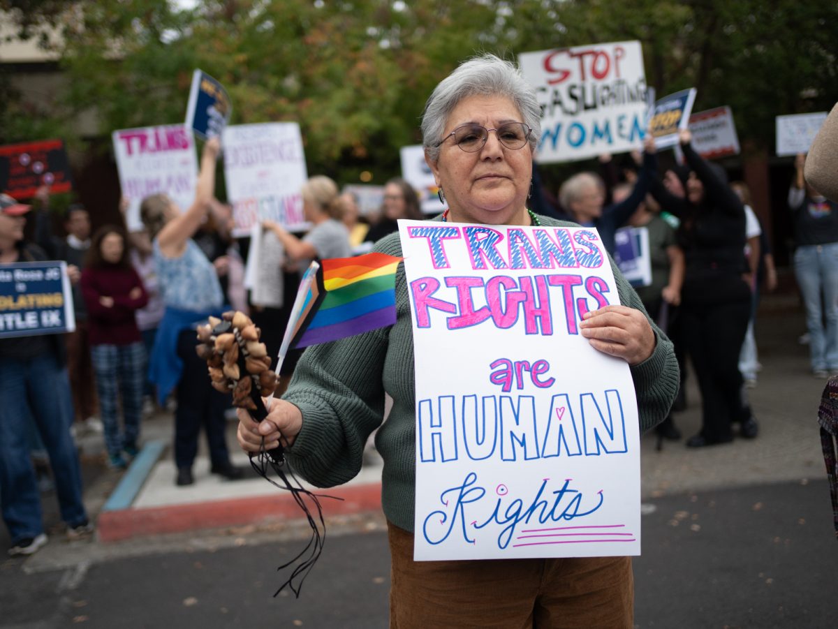 A supporter of a trans athlete's rights to participate on the SRJC women's volleyball team steps in front of the opposing demonstrators holding a sign that says "Trans Rights Are Human Rights" ahead of Wednesday night's matches against American River on Wednesday, Oct. 8.