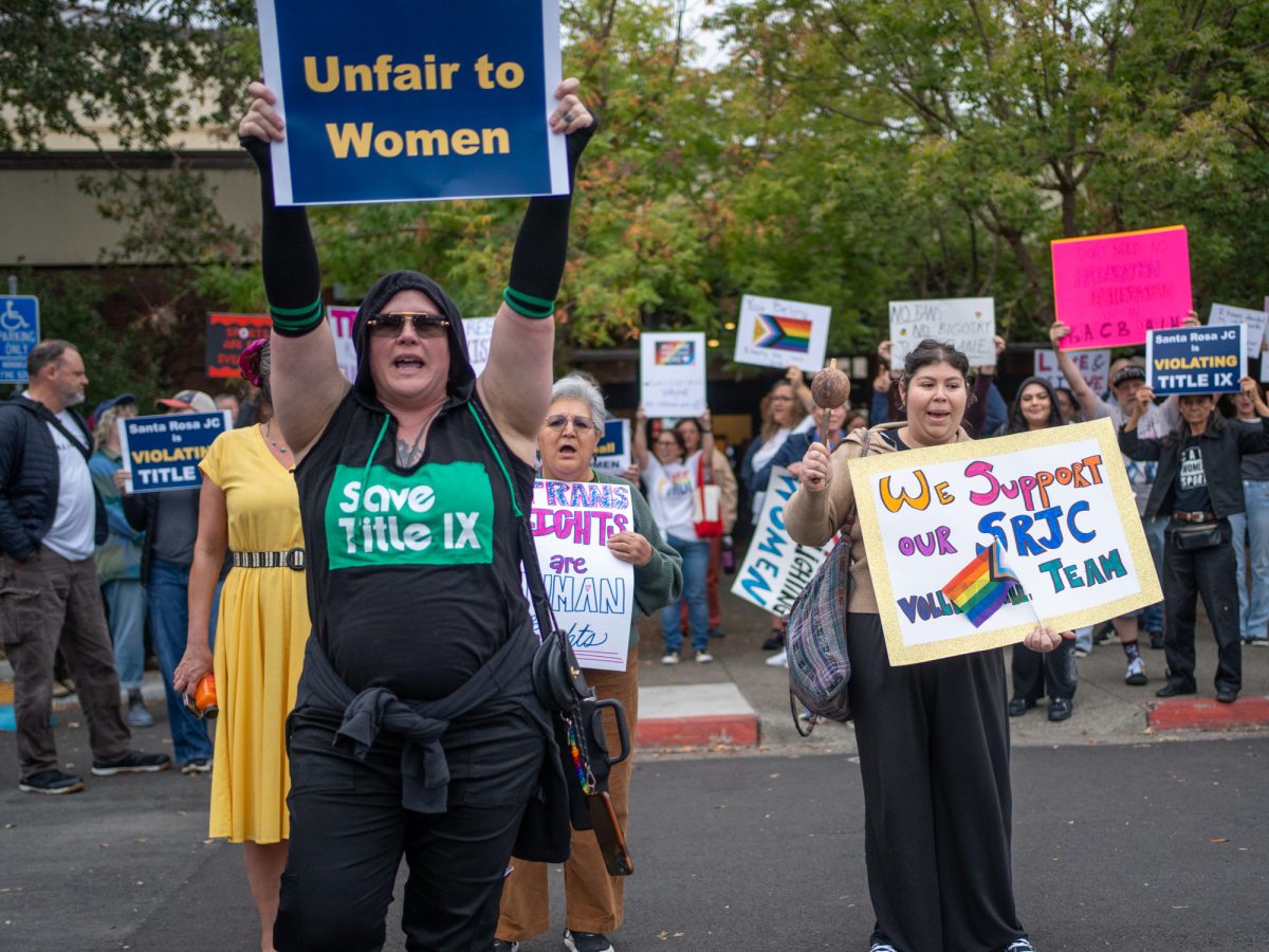 An community member opposed of a trans athlete's rights to participate on the SRJC women's volleyball team steps in front of the supporting demonstrators holding a sign that says "Unfair to Women" ahead of Wednesday night's matches against American River on Wednesday, Oct. 8.
