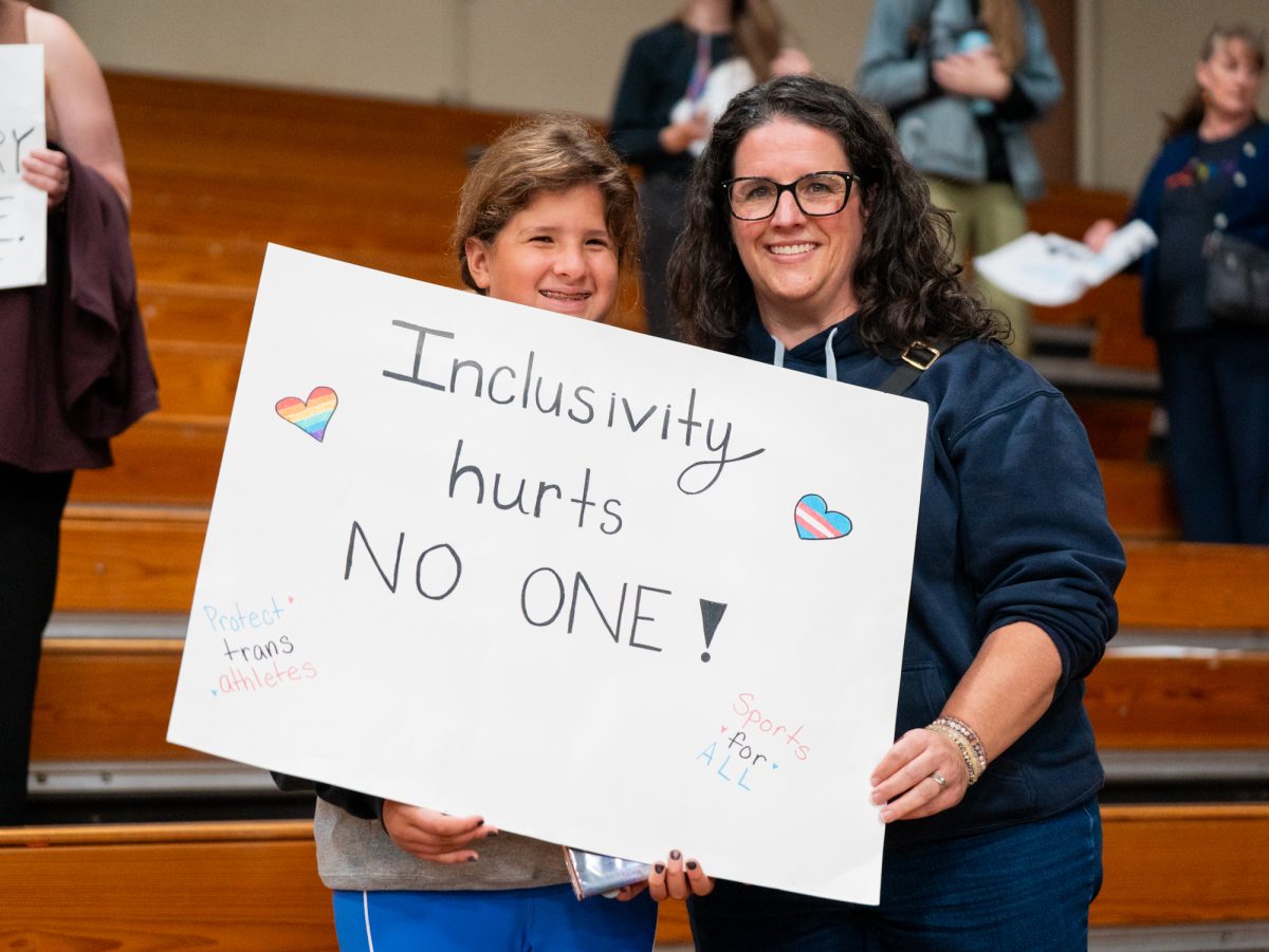 Supporters of a trans athlete's right to play on the SRJC women's volleyball team hold up a sign that says "Inclusivity Hurts No One! Protect Trans Athletes and Sports For All"