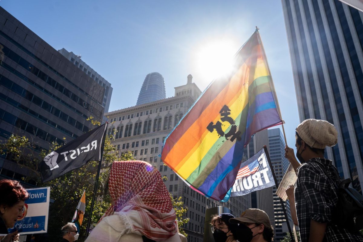 A demonstrator’s translucent pride flag with transgender symbol ripples in the Bay Area breeze at a No Kings protest Saturday, Oct. 18, 2025 in San Francisco, Calif.