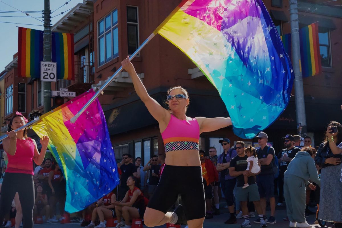 A member of the Harvey Milk Pride Colorguard, a new San Francisco colorguard group, is all smiles during one of their performances at the Castro Street Fair on Sunday Oct. 5, 2025. 