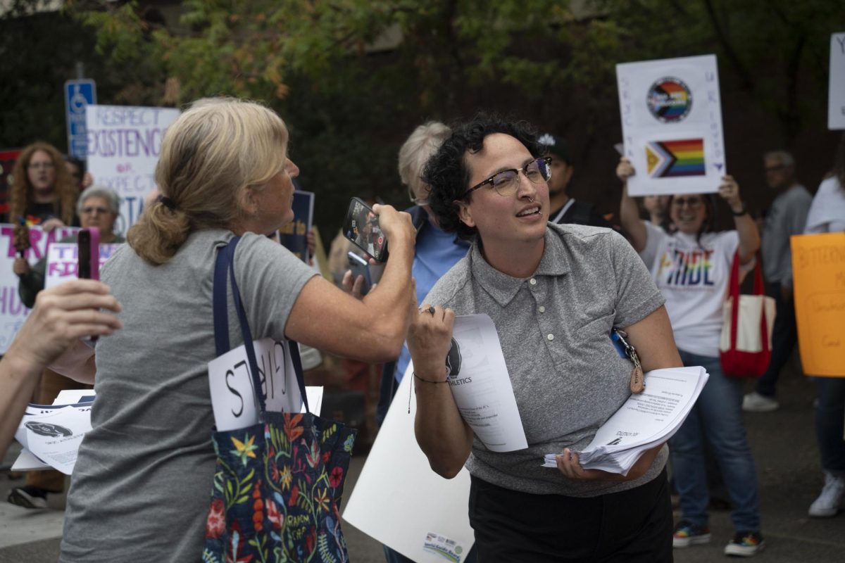 (From left to right) Beth Bourne, Chair of Yolo County's chapter of Moms for Liberty records and questions Corrina Wells, the SRJC Director of Student Life and Cultural Programs while they hand out packets to demonstrators in support of the transgender athlete on Wednesday, Oct. 8, 2025 in front of Haehl Pavilion. The packet contained information promoting "joyful energy" and not engaging with "antagonizing behaviors".