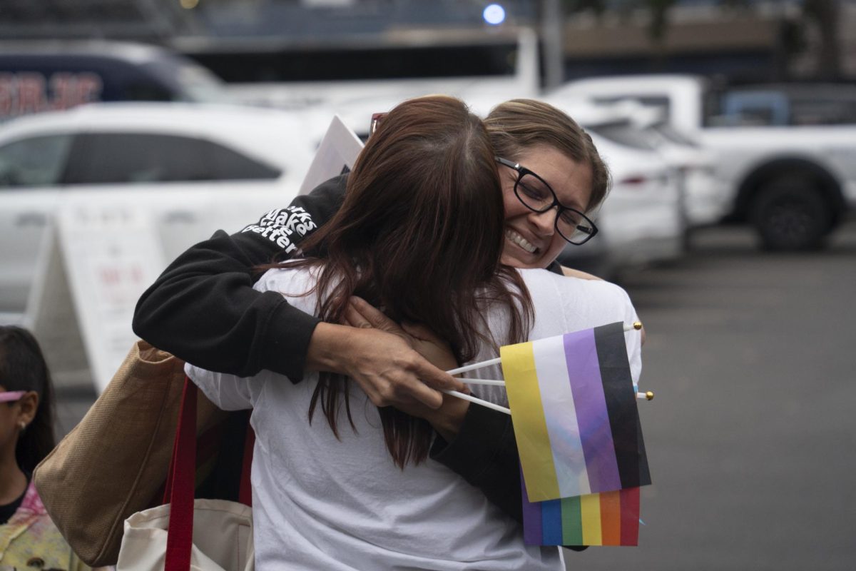 Two demonstrators embrace upon arriving to the SRJC women's volleyball match on Wednesday, Oct. 8, 2025 in front of Haehl Pavilion.