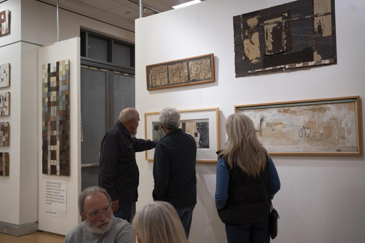 Alan Azhderian, left, shows a couple of attendees the details of a multimedia collage piece during the closing reception of the "Context/Content" exhibition on Dec. 4, 2025 in the Robert F. Agrella Gallery.