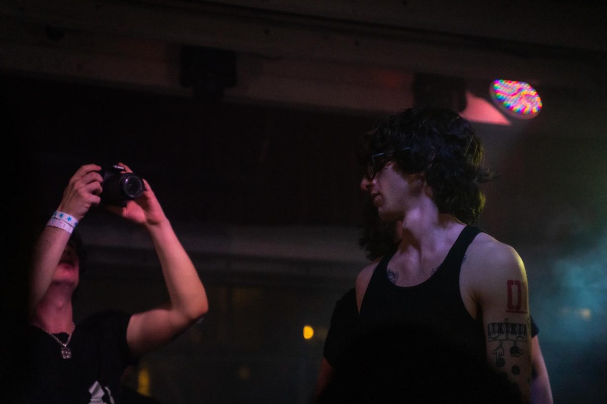 myspacemark's (right) longtime friend and videographer Jack O'Brien (left) captures a rare moment of calm amidst the otherwise electric environment of the pluggnb artist's first-ever show Dec. 4, 2025 at the DNA Lounge in San Francisco.