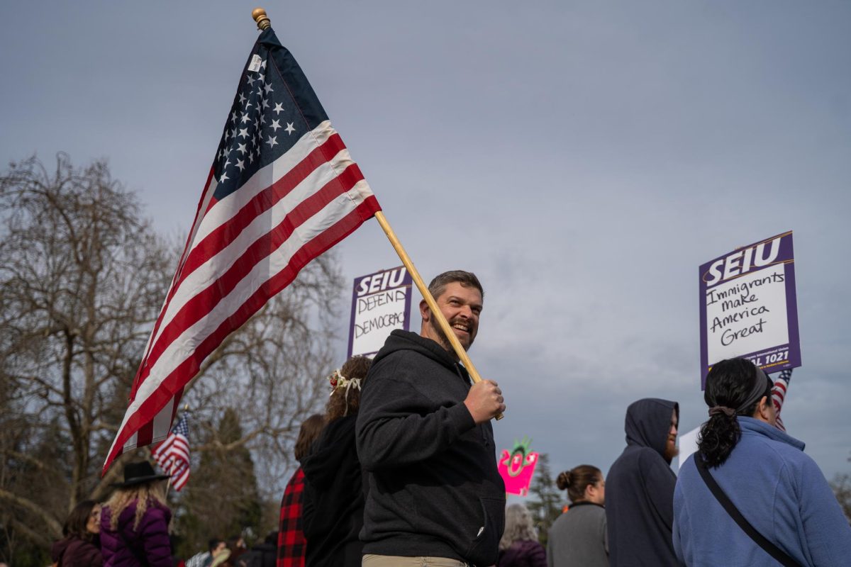 A protestor waves an American flag to a crowd of hundreds at the Free America Walkout on Mendocino Avenue in front of Santa Rosa Junior College Jan. 20, 2026. 