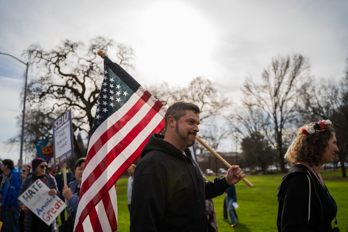 A protestor marches through the crowd holding an American flag at the Free America Walkout on Mendocino Avenue in front of Santa Rosa Junior College Jan. 20, 2026. 
