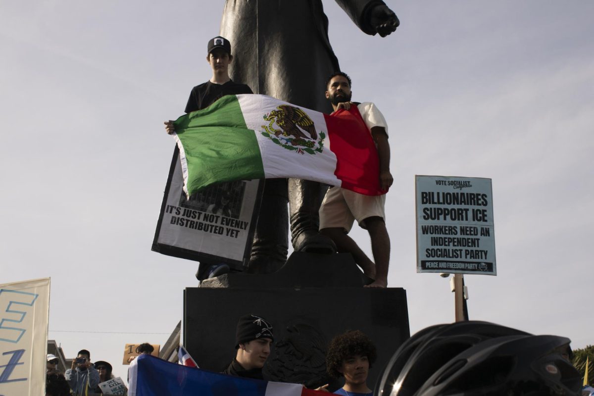 Protesters climb the Miguel Hidalgo Statue while holding the Mexican flag during the ICE Out protest at Dolores Park Friday, Jan. 30, 2026.