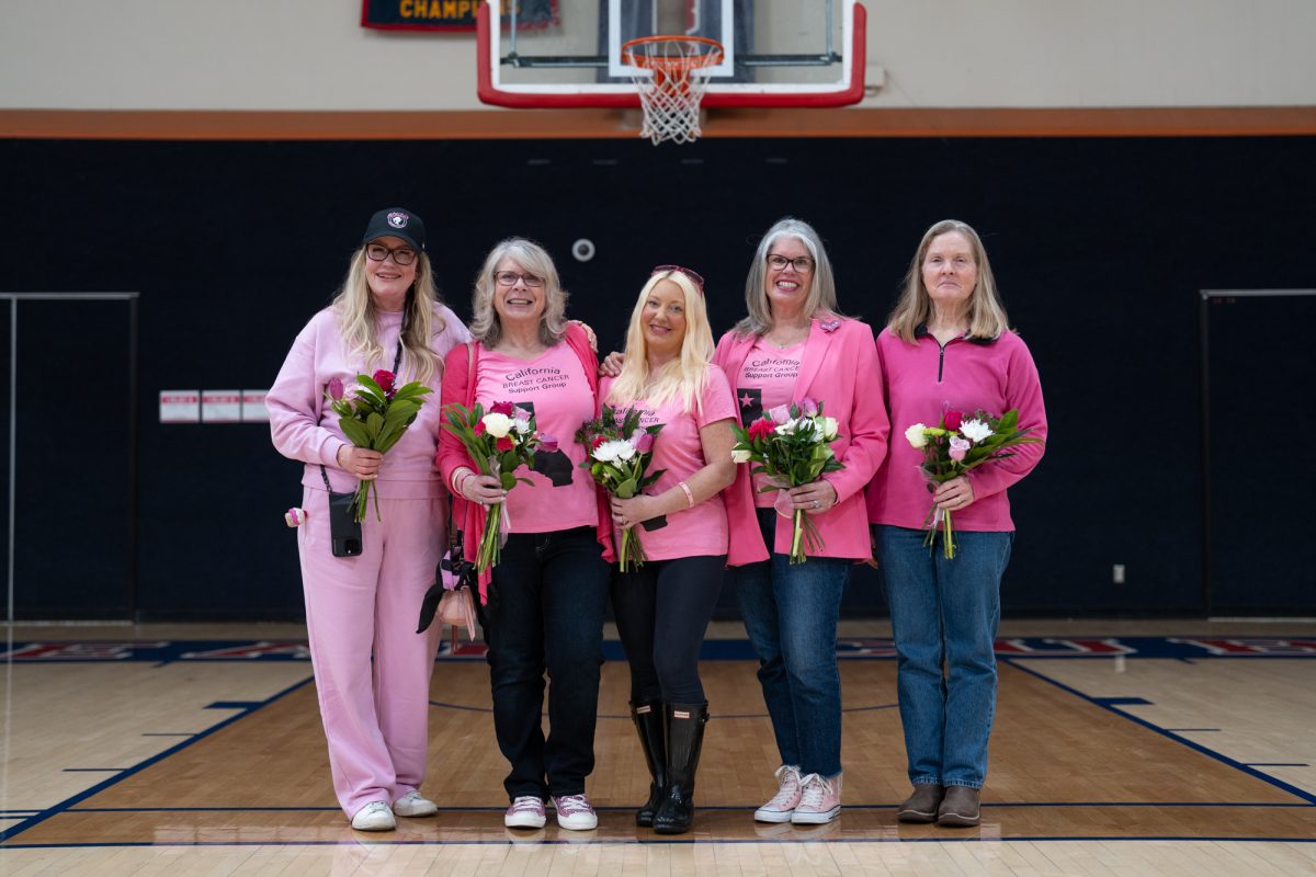 (From left) Breast cancer survivors Lauren Feagin, Michele Salazar, Ariana Balakrishnan, Cindy McElrath and Rachel Romes Grossmann gather for a photo-op after being recognized at the women's basketball's Play4Kay game Feb. 10 in Haehl Pavilion.