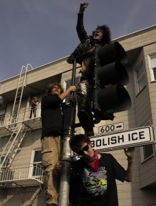 Protesters make their voices heard while they hang onto a traffic light, chanting to abolish Immigration and Customs Enforcement during the ICE Out protest at Dolores Park in San Francisco, Jan. 30, 2026.
